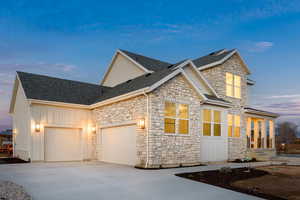 View of front of property with an attached garage, board and batten siding, and stone siding