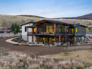 Rear view of house with a patio area, a balcony, and a mountain view