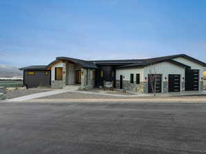 View of front of property featuring stone siding, a standing seam roof, and a garage