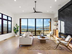 Living room with a ceiling fan, light wood-type flooring, a tile fireplace, recessed lighting, and a water and mountain view