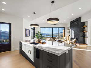 Kitchen with a mountain view, light stone countertops, open floor plan, pendant lighting, and a center island with sink