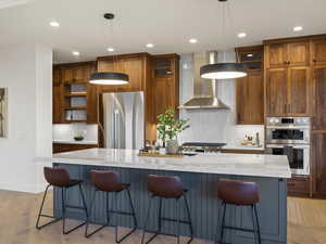 Kitchen featuring a breakfast bar, light wood finished floors, light stone counters, and stainless steel appliances