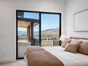 Carpeted bedroom featuring access to outside, multiple windows, and a water and mountain view