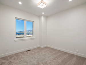 Spare room featuring light carpet, a mountain view, and recessed lighting
