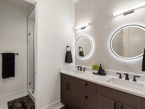 Full bath featuring double vanity and a shower stall