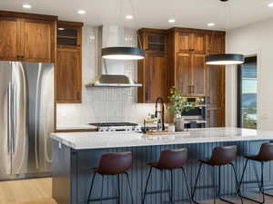 Kitchen featuring stainless steel appliances, light stone counters, a breakfast bar, and glass fronted cabinets