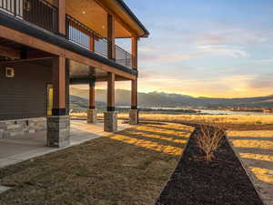 View of grassy yard with a patio, a mountain view, and a balcony