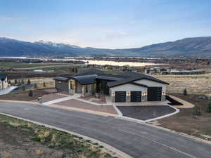 View of front facade with stone siding, a mountain view, a garage, and driveway