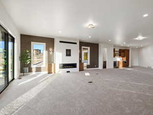 Unfurnished living room featuring carpet, a large fireplace, recessed lighting, and beverage cooler