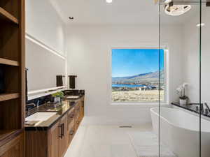 Full bathroom featuring double vanity, a freestanding tub, recessed lighting, and a water view