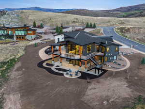 Back of property with a balcony, a patio, a mountain view, and roof with shingles