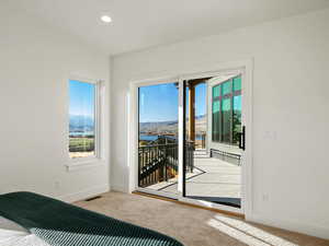 Bedroom featuring light colored carpet, access to exterior, recessed lighting, and a water and mountain view