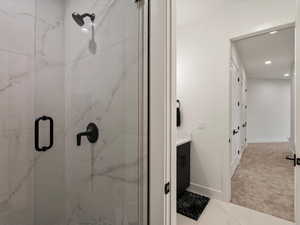 Bathroom featuring vanity, a marble finish shower, recessed lighting, and light carpet