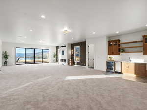 Unfurnished living room featuring bar with sink, a mountain view, beverage cooler, recessed lighting, and light colored carpet
