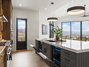 Kitchen with a mountain view, stainless steel stove, light stone countertops, and hanging light fixtures
