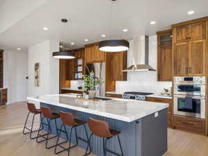 Kitchen with a kitchen breakfast bar, wood finish cabinetry, light wood-style floors, light stone countertops, and a spacious island