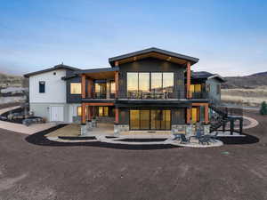 Back of property featuring a balcony and stone siding