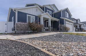 Craftsman house featuring board and batten siding, an attached garage, a gate, driveway, and stone siding