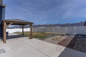 Fenced backyard with a mountain view, a gazebo, and a patio