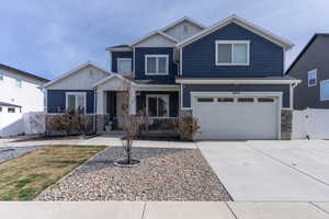 Craftsman house featuring stone siding, board and batten siding, a gate, a garage, and driveway