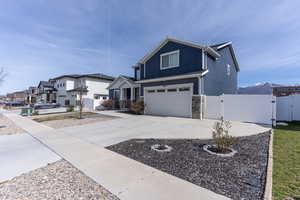 View of front of property with a gate, a garage, stone siding, driveway, and a residential view