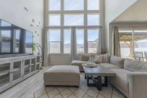 Living room featuring a high ceiling, light wood finished floors, a mountain view, and plenty of natural light