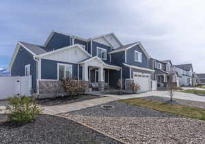 View of front of home featuring board and batten siding, driveway, a gate, a garage, and stone siding