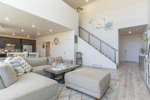 Living area with recessed lighting, light wood-style floors, and a high ceiling