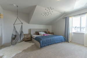 Carpeted bedroom with vaulted ceiling and baseboards