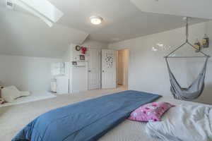 Carpeted bedroom with vaulted ceiling and a skylight