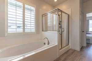 Bathroom with ensuite bathroom, a shower stall, wood finished floors, and a garden tub