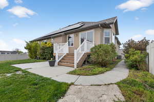 Bungalow-style home featuring roof mounted solar panels, stucco siding, and roof with shingles