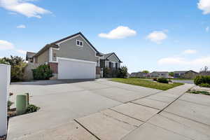 View of front facade with brick siding, driveway, a residential view, a front lawn, and an attached garage