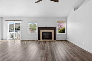 Unfurnished living room with ceiling fan, dark wood finished floors, a tiled fireplace, and lofted ceiling