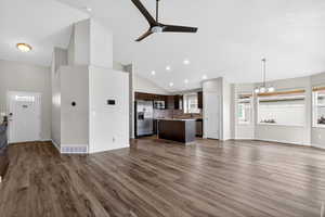 Unfurnished living room with suspended lighting, a ceiling fan, vaulted ceiling, and dark wood-style flooring