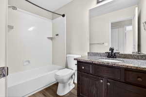 Bathroom with vanity, tub / shower combination, and dark wood finished floors