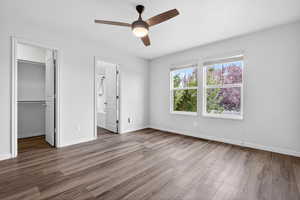 Unfurnished bedroom featuring a walk in closet, dark wood-style floors, ceiling fan, and connected bathroom