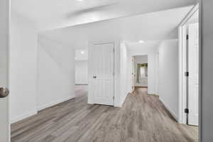 Corridor with light wood-type flooring and recessed lighting