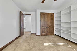 Unfurnished bedroom with light colored carpet, a ceiling fan, and a closet