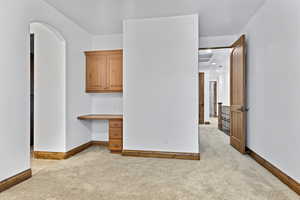 Unfurnished bedroom featuring built in desk, light carpet, and recessed lighting