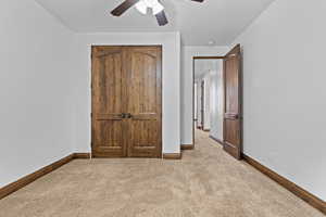 Unfurnished bedroom featuring carpet floors, a closet, and a ceiling fan