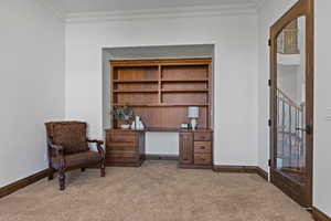 Sitting room with light colored carpet, ornamental molding, and a desk