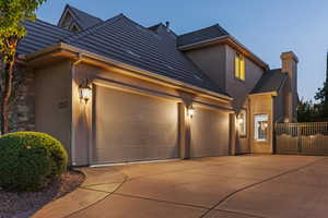 View of front facade with an attached garage, stucco siding, concrete driveway, and a chimney
