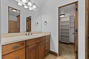 Bathroom featuring vanity, a walk in closet, and light colored carpet