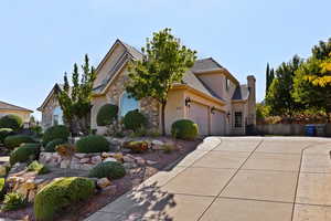 View of front of property featuring stone siding, stucco siding, a garage, and concrete driveway