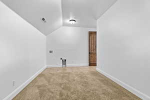 Additional living space featuring light colored carpet and lofted ceiling