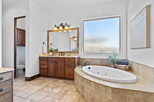 Full bathroom featuring vanity, stone tile floors, and a whirlpool tub
