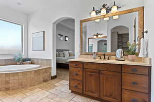 Ensuite bathroom with stone tile flooring, vanity, and a garden tub