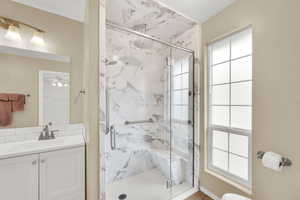 Bathroom featuring a marble finish shower and vanity