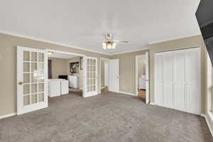 Unfurnished bedroom featuring french doors, ornamental molding, carpet flooring, a closet, and a ceiling fan